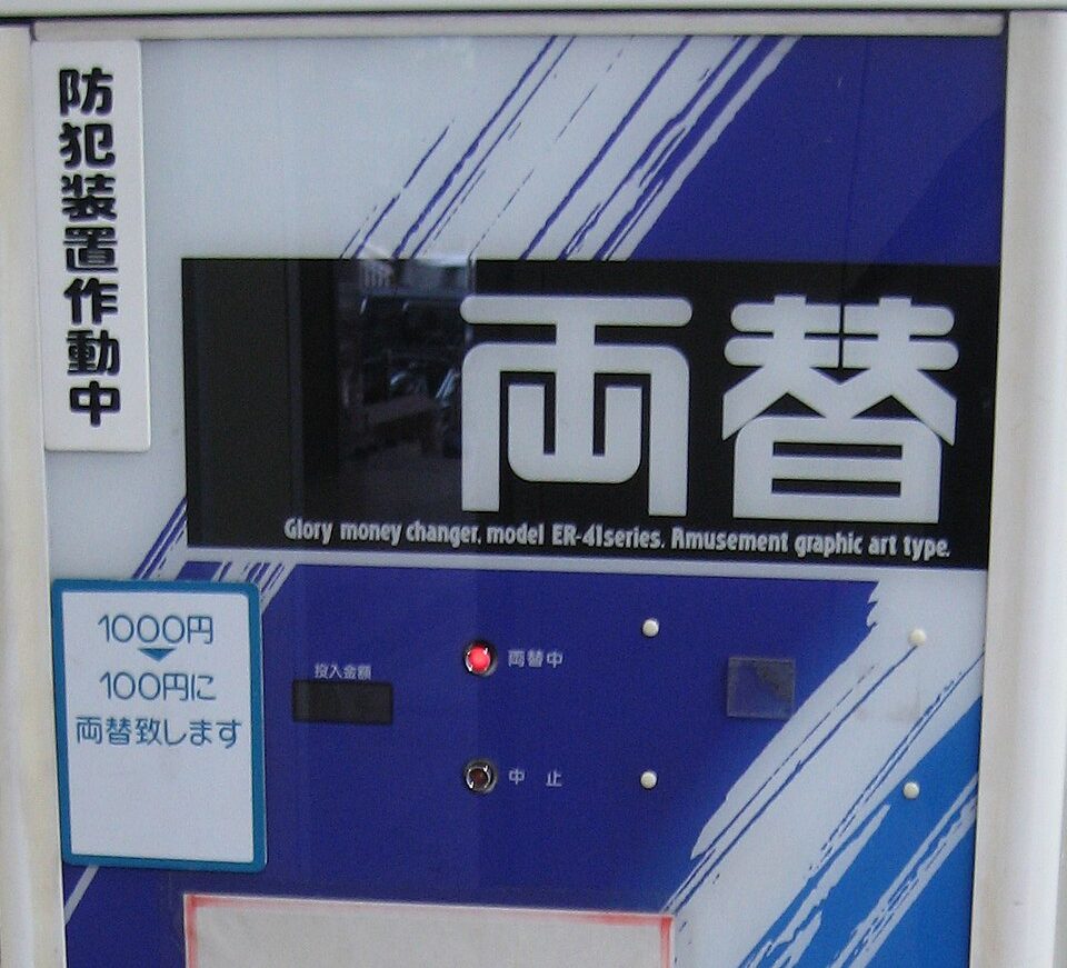위쪽에 '환전'을 뜻하는 일본어 료가에(両替)가 쓰인 파란색과 흰색의 환전기