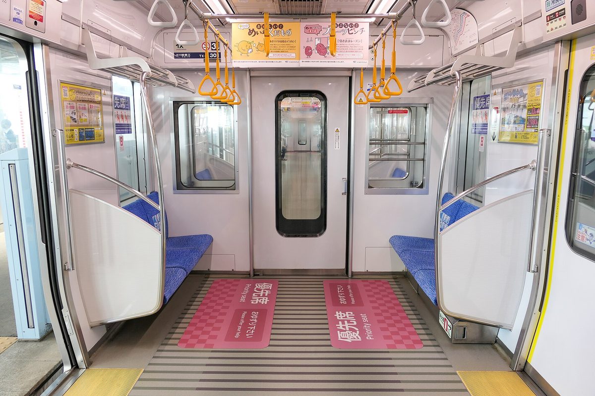 Empty priority seats at the end of a Tsukuba Express car, with a pink floor marking in front of them