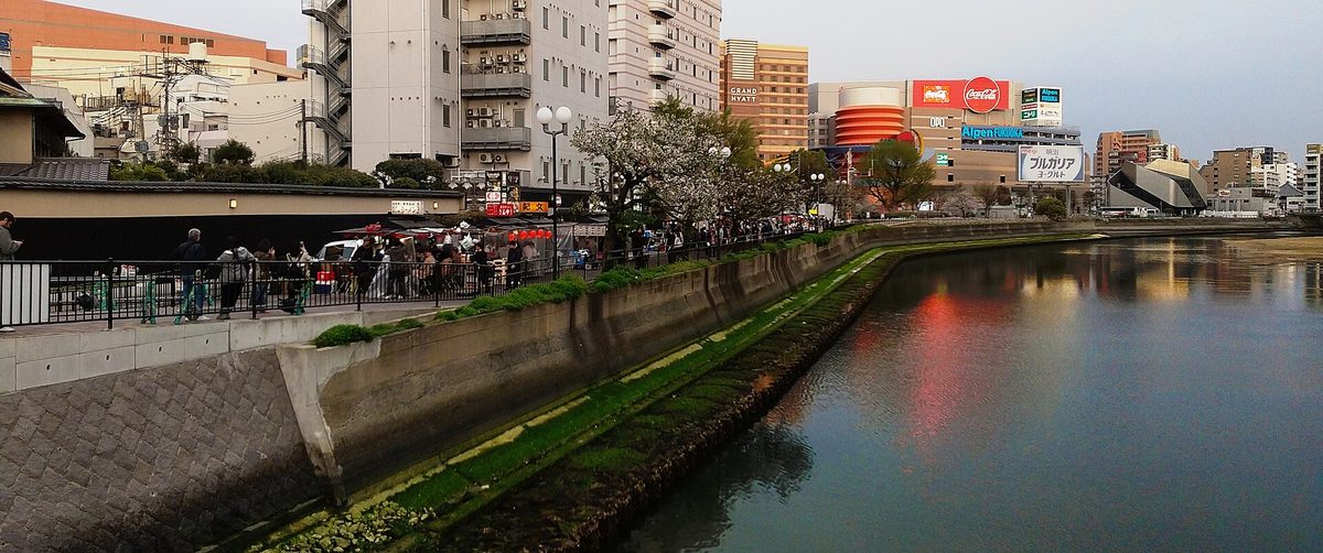 Food stall carts lined up along a river promenade at dusk