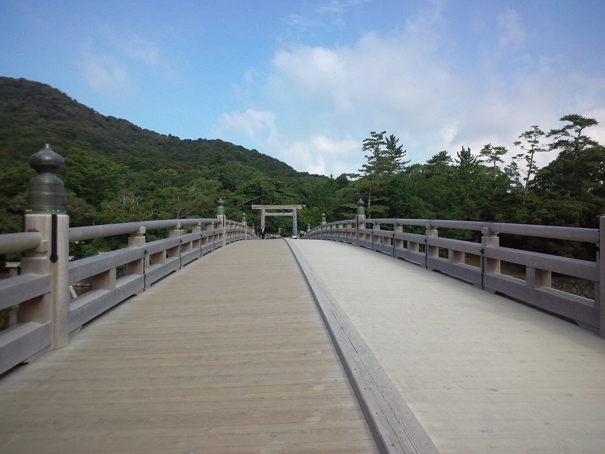 The long wooden Uji Bridge leading to a torii gate in the forest